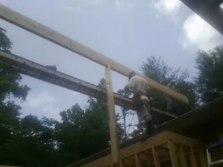 Carpenter setting a ridge beam over a new addition frame — Ice Dam Removal by Roofing Brothers in Highland