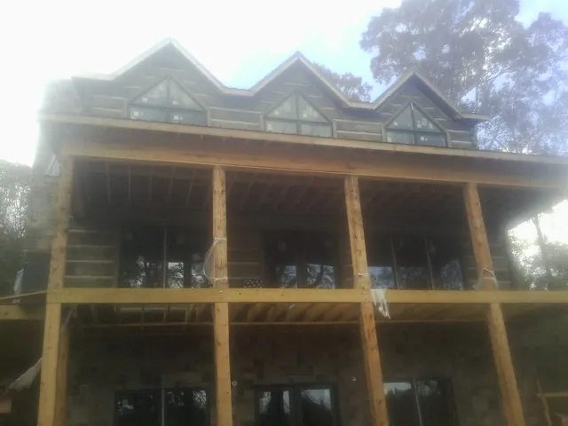 Dormers and porch framing on a large log home under construction — Roof Coating work by our crew in Highland